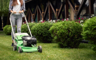 Horizontal Crop Of Woman In Casual Outfit Using Lawn Mower On Ba