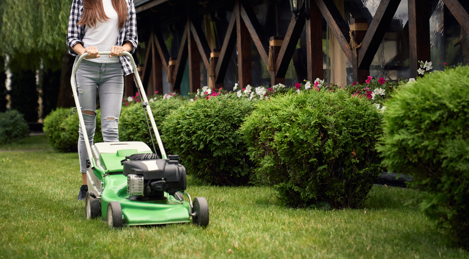Horizontal Crop Of Woman In Casual Outfit Using Lawn Mower On Ba